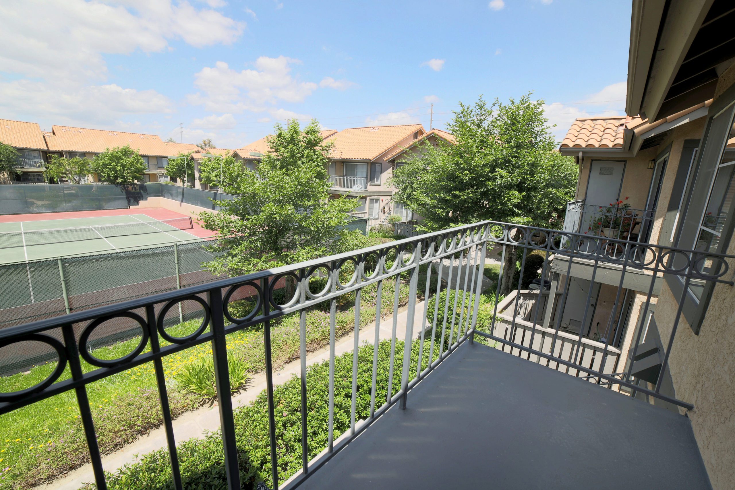 One Bedroom Apartments in Anaheim CA - Le Med - Balcony with a Storage Area, Railing, and a View of the Tennis Court
