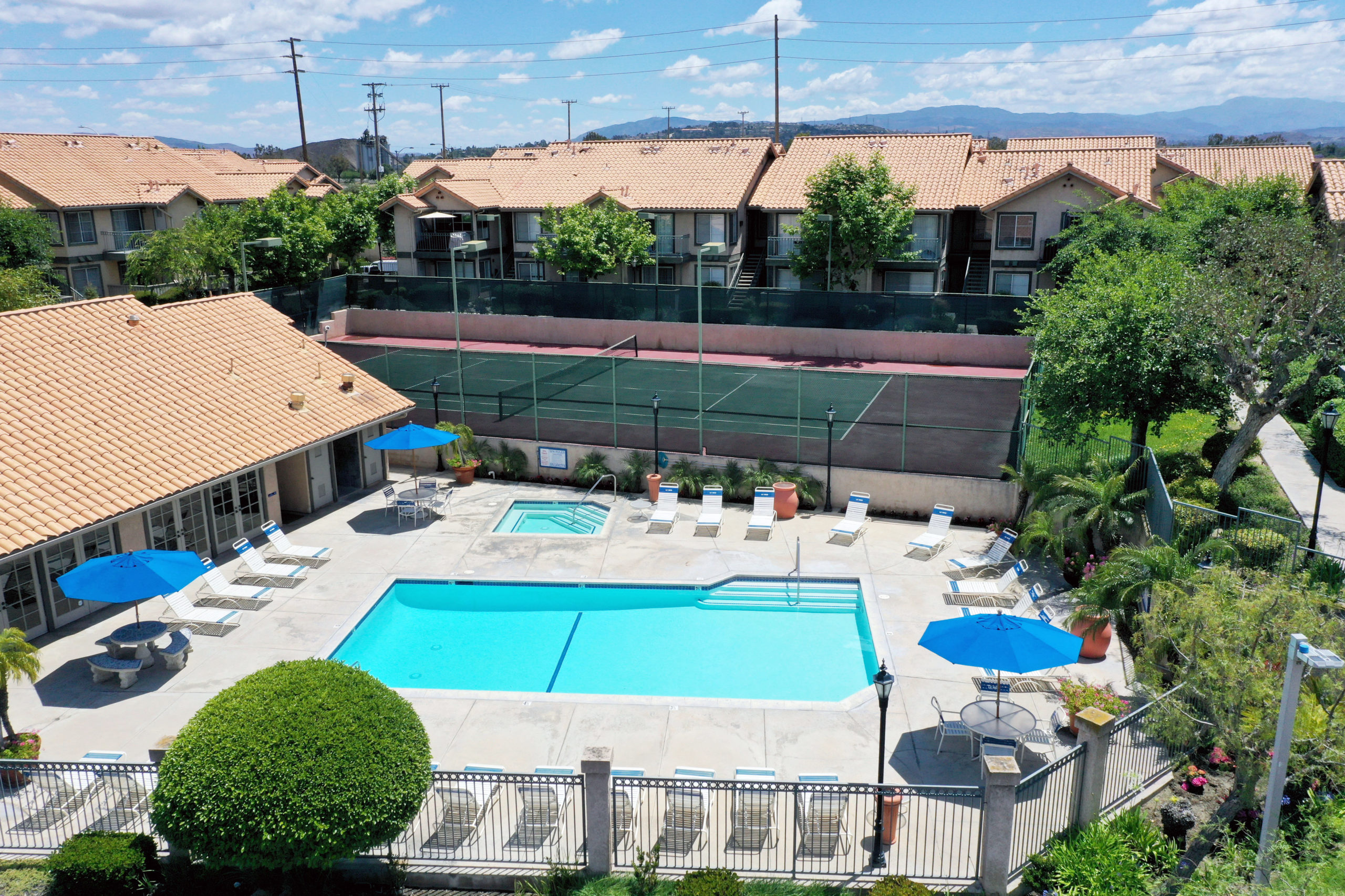 Apartments in Anaheim for Rent - Le Med - Swimming Pool Surrounded by Lounge Chairs, Covered Seating Areas, and Lush Landscaping